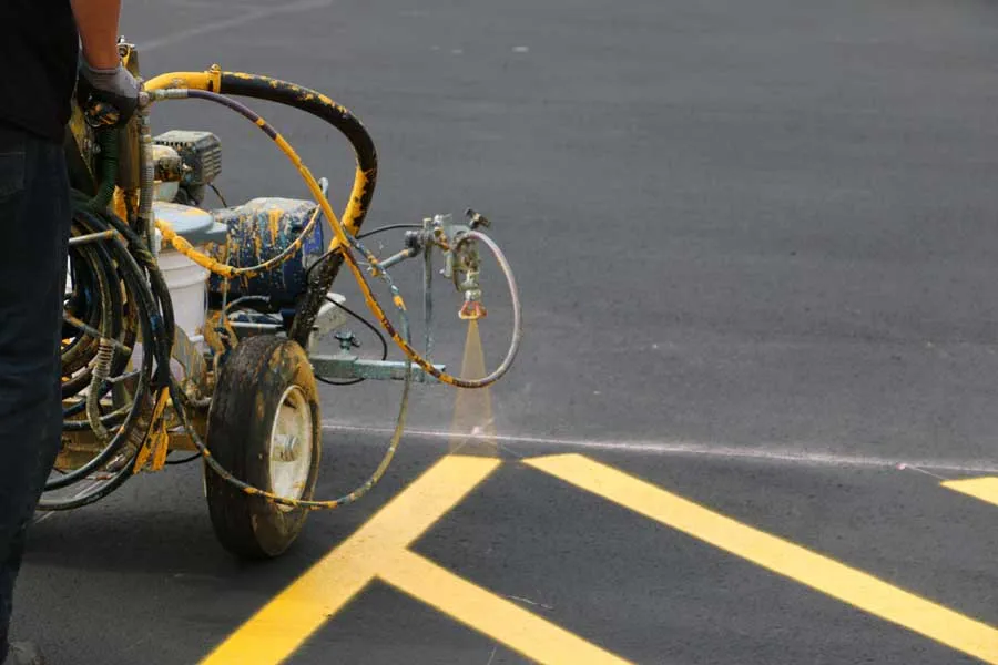 Striping machine painting fresh yellow lines on a commercial parking lot