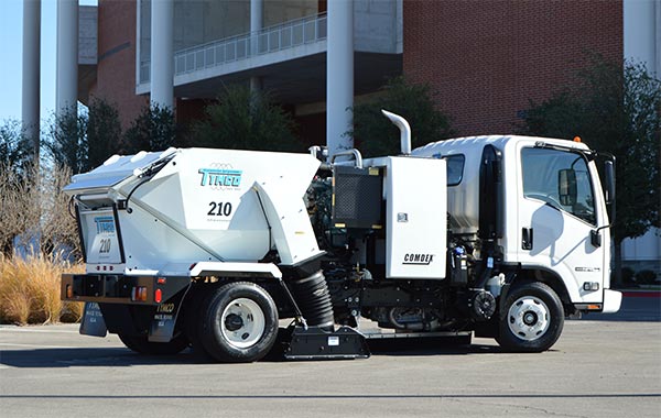 Parking lot sweeper truck cleaning a commercial shopping center lot